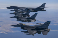 US Air Force B-1B bomber, top, flies in formation with US Air Force F-16 '013' fighter jets ov...png