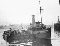 A damaged Lockheed P-38 on part of an assault barge is brought into port at the Dufferin Docks...jpg