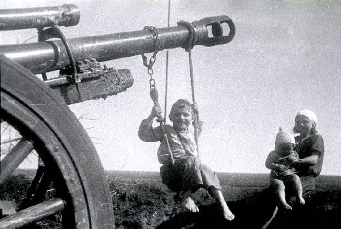 Russian boy swings on Nazi cannon which is left by German troops in Soviet
