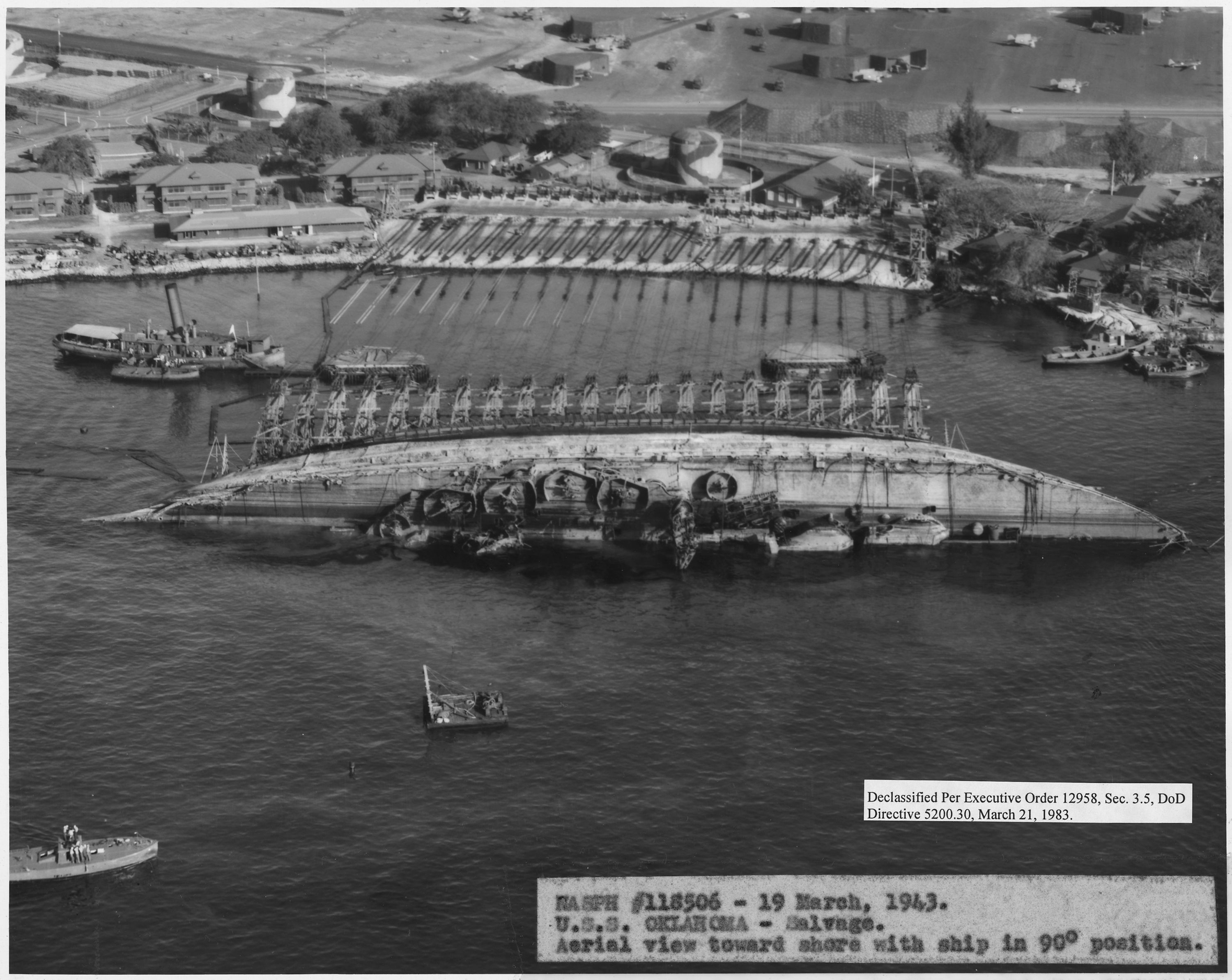 USS_Oklahoma-_Salvage_Aerial_viwe_toward_shore_with_ship_in_90_degree_posit